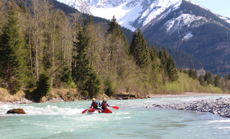 Ein Kajakfahrer auf einem klaren Fluss umgeben von Bergen und Wäldern. Die Berglandschaft ist beeindruckend und die Natur wirkt lebendig. | © MAP-Erlebnis