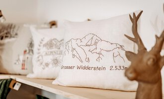 A pillow featuring an image of the Great Arberstone, standing at a height of 2,533 meters. In the background, a decorative antler head is visible. | © Herzstichle | Ninja Matt
