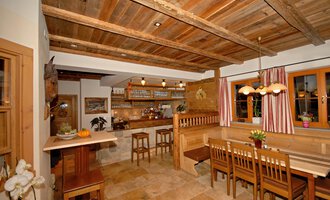 A cozy kitchen with wood decor and bright lighting. There are tables, chairs, and a bar with an inviting atmosphere. | © Michl das Steakhaus | Johannes Littich