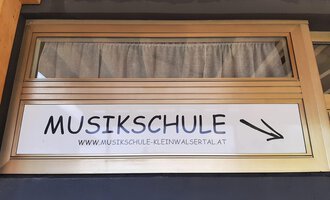 Ein Schild mit der Aufschrift "MUSIKSCHULE" weist auf eine Musikschule hin. Die Adresse ist ebenfalls angegeben. | © Kleinwalsertal Tourismus | Veronika Senn