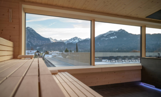 A modern wellness oasis amidst mountains and forest. People relax in a harmonious environment with green plants and a clear sky. | © Tourismus Oberstdorf