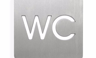 A metallic sign with the inscription "WC". The sign has rounded corners and a modern font.
