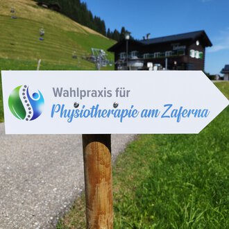 © Kleinwalsertal Tourismus | N. Lughammer A sign points to the election practice for physiotherapy at Zaferna. The surroundings are green and mountainous, ideal for relaxation. | © Kleinwalsertal Tourismus | N. Lughammer