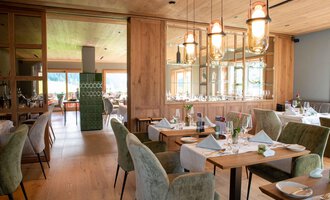 Ein modernes Restaurant mit eleganter Holzausstattung. Die Tische sind liebevoll gedeckt und die Beleuchtung ist warm und einladend. | © Almhof Rupp | Lukas Kind