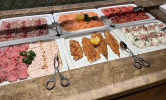 Ein Tisch mit einer Auswahl an verschiedenen Aufschnittsorten, einschließlich Schinken, Lachs und Käse. Die Platten sind schön angerichtet und mit frischen Kräutern dekoriert. | © Almhof Rupp | Lukas Kind