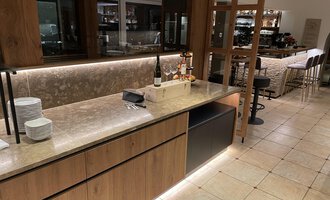 Eine moderne Bar mit einer eleganten Holz- und Steintheke. Der Raum ist gut beleuchtet und bietet eine gemütliche Atmosphäre. | © Almhof Rupp | Lukas Kind