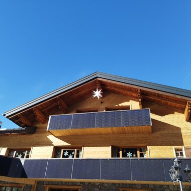 Ein modernes Holzhaus mit einem Balkon und Photovoltaik-Modulen. Der klare blaue Himmel sorgt für eine freundliche Atmosphäre. | © Kleinwalsertal Tourismus | N. Lughammer