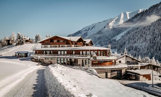 Ein modernes Chalet in den Bergen, umgeben von Schnee. Die idyllische Winterlandschaft lädt zum Entspannen ein.