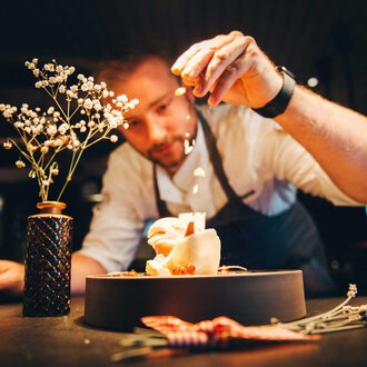 © Hotel Birkenhöhe | Stefan Klauser Ein Koch verziert mit viel Liebe und Geschick ein Gericht. Im Hintergrund steht eine kleine Blume in einer Vase. | © Hotel Birkenhöhe | Stefan Klauser