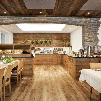 Ein gemütliches Restaurant mit Holzdekor und einem einladenden Buffet. Die Tische sind elegant gedeckt mit grünen Servietten. | © Robert Haller GmbH c/o Hotel Steinbock