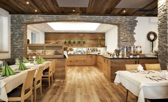 Ein gemütliches Restaurant mit Holzdekor und einem einladenden Buffet. Die Tische sind elegant gedeckt mit grünen Servietten. | © Robert Haller GmbH c/o Hotel Steinbock