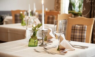 Ein elegant gedeckter Tisch mit Kerzenlicht und stilvollen Gläsern. Blumen und dekorative Elemente sorgen für eine einladende Atmosphäre. | © Robert Haller GmbH c/o Hotel Steinbock