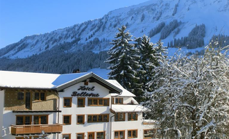 Ein malerisches Hotel im Schnee mit majestätischen Bergen im Hintergrund. Die Landschaft ist winterlich und ruhig, perfekt für einen Urlaub in den Bergen. | © Hotel Bellevue | I. Malouvier