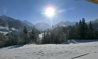 Eine sonnige Winterlandschaft mit schneebedeckten Bergen und Bäumen. Der Himmel ist klar blau und die Sonne strahlt hell. | © Hotel Bellevue | I. Malouvier