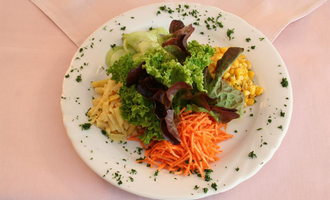 Ein bunter Salat auf einem weißen Teller mit verschiedenen Gemüsesorten. Darunter sind grüner Salat, Karottenstreifen, Mais und Gurken zu sehen. | © Hotel Bellevue | Werbewind GmbH