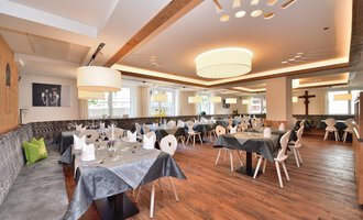 Ein elegantes Restaurant mit Holzfußboden und modernen Tischen. Die Tische sind schön gedeckt und die Beleuchtung ist sanft. | © Hotel Tradizio GmbH | Werbewind GmbH