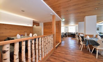 Ein modern gestaltetes Restaurant mit Holzwänden und einem einladenden Ambiente. Tische sind mit gedeckten Tellern vorbereitet, und der Boden ist aus Holz. | © Hotel Tradizio GmbH | Werbewind GmbH