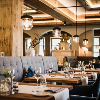 © Verwöhn- & Wellnesshotel Walserhof| Aileen Melucci Ein stilvolles Restaurant mit eleganten Tischen und bequemen Sitzplätzen. Die gemütliche Atmosphäre wird durch sanfte Beleuchtung und natürliche Materialien hervorgehoben. | © Verwöhn- & Wellnesshotel Walserhof| Aileen Melucci