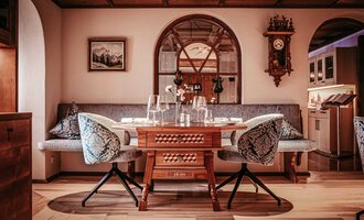 Ein elegantes Esszimmer mit einem großen Holztisch und bequemen Sitzgelegenheiten. Es hat eine gemütliche Atmosphäre mit dekorativen Elementen und sanftem Licht. | © Hotel Birkenhöhe | Sascha Gast