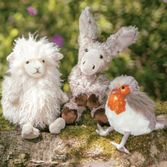 © Rohn - Kinder, Trends und mehr | Wrendale Three cute plush toys are sitting on a tree trunk: a sheep, a donkey, and a bird. They look friendly and are surrounded by a natural environment. | © Rohn - Kinder, Trends und mehr | Wrendale