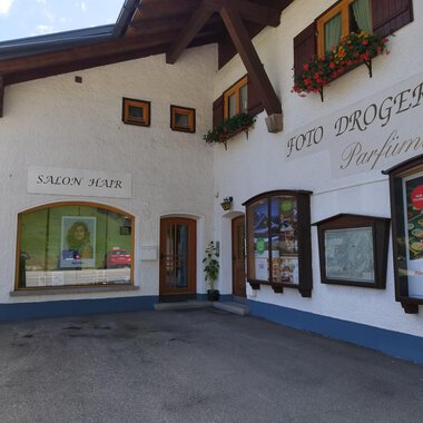 Ein charmantes Gebäude mit blühenden Fensterkästen. Es beherbergt einen Salon und eine Drogerie. | © Kleinwalsertal Tourismus