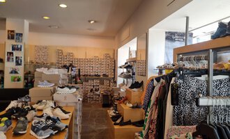 Ein Schuhgeschäft mit einer Vielzahl von Schuhen und Kleidung. Die Regale sind voll mit Schuhkartons und Bekleidung hängt auf Kleiderstangen. | © Schuhhaus Schuster | Marietta Diehl