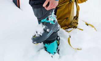 Ein Mann repariert Skiausrüstung und montiert einen Skischuh. Im Hintergrund stehen zahlreiche Ski. | © Kleinwalsertal Tourismus | Oliver Farys