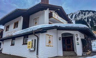 Ein charmantes Gebäude im alpinen Stil, umgeben von Schnee und Bergen. Die Fassade ist weiß und lädt zum Verweilen ein. | © Trattoria Pomo d'oro | K. Harmat-Hegedüs
