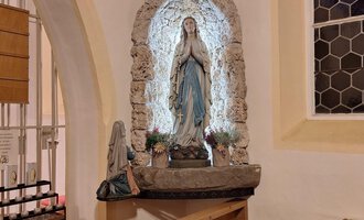 Eine Statue der Jungfrau Maria in einer Kirche, umgeben von Steinmauerwerk. Der Bereich ist sanft beleuchtet und bietet eine ruhige Atmosphäre. | © Unterwestegg-Kapelle Maria Hilf | Tanja Ritsch