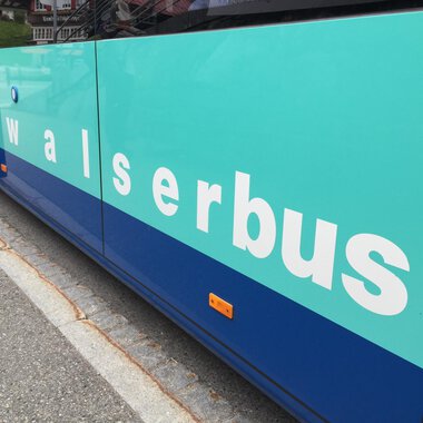 Ein Bus in turquoise und blau mit der Aufschrift „walserbus“. Die Schrift ist gut lesbar und befindet sich an der Seite des Fahrzeugs. | © Kleinwalsertal Tourismus