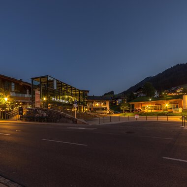 A picturesque place at night with illuminated buildings and gentle hills in the background. The calm atmosphere invites you to linger. | © Kleinwalsertal Tourismus |  Steffen Berschin