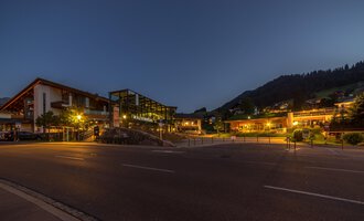 Ein malerischer Ort bei Nacht mit beleuchteten Gebäuden und sanften Hügeln im Hintergrund. Die ruhige Atmosphäre lädt zum Verweilen ein. | © Kleinwalsertal Tourismus |  Steffen Berschin