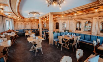 Ein gemütliches Restaurant mit Holzmöbeln und blauen Sitzbänken. Die Atmosphäre ist warm und einladend, ideal für gesellige Zusammenkünfte.