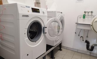 A laundry room with several washing machines on a tiled floor. In the background, there is a sink. | © Kleinwalsertal Tourismus | N. Lughammer