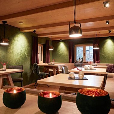 Ein stilvolles Restaurant mit Holzinterieur und gedämpftem Licht. Die Tische sind festlich gedeckt und schaffen eine gemütliche Atmosphäre.