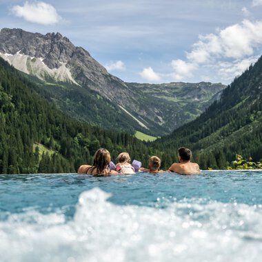 Ein entspannender Pool mit Menschen, die die Aussicht auf die Berge und die Natur genießen. Die Landschaft ist grün und die Berge sind majestätisch im Hintergrund.