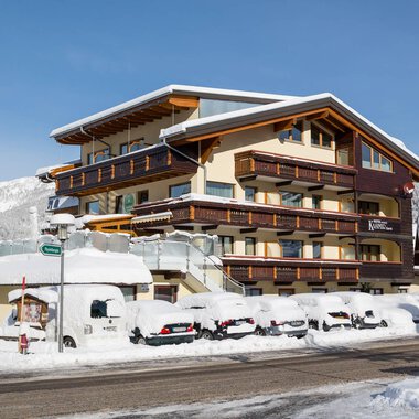 Ein wunderschönes Hotel im Winter mit Schnee bedeckten Autos. Die Umgebung ist winterlich und malerisch.
