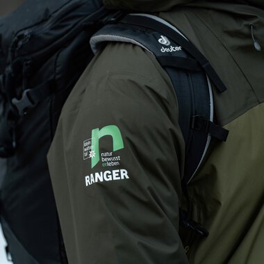 Nahaufnahme eines Rangers im dunklen grünen Jacke mit  | © Kleinwalsertal Tourismus eGen • Fotograf: Basti Heckl