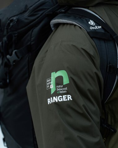 Nahaufnahme eines Rangers im dunklen grünen Jacke mit  | © Kleinwalsertal Tourismus eGen • Fotograf: Basti Heckl