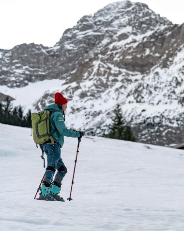 Zwei Skifahrer in Winterkleidung auf Schneeschuhen in einer verschneiten Berglandschaft, im Hintergrund hohe, teils schneebedeckte Berge. | © Kleinwalsertal Tourismus eGen • Fotograf: Basti Heckl