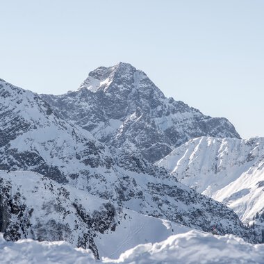 Panoramablick auf den verschneiten Widderstein-Gipfel und umliegende Berge in winterlicher Landschaft. | © Kleinwalsertal Tourismus eGen • Fotograf: Dominik Berchtold