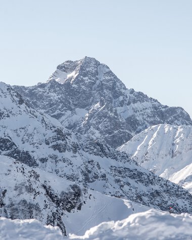 Panoramablick auf den verschneiten Widderstein-Gipfel und umliegende Berge in winterlicher Landschaft. | © Kleinwalsertal Tourismus eGen • Fotograf: Dominik Berchtold
