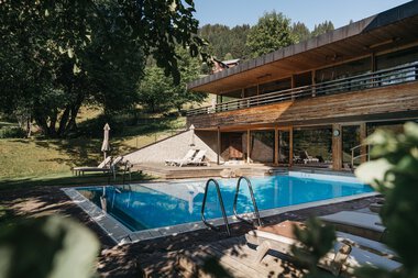 Pool im Naturhotel Chesa mit Blick auf den Garten und die umliegende Natur, sonnig und einladend. | © Kleinwalsertal Tourismus eGen • Fotograf: Oliver Farys