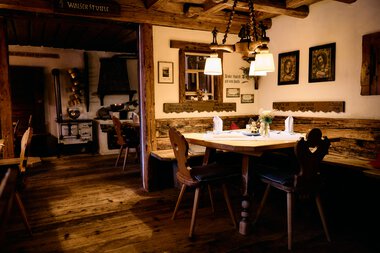 Gemütliches Esszimmer im rustikalen Stil mit Holztischen, Stühlen und warmem Licht. Dekorative Bilder an der Wand. | © Kleinwalsertal Tourismus eGen • Fotograf: Oliver Farys