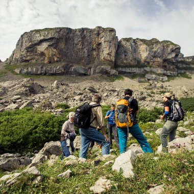 Gruppen von Wanderern unterwegs in einer bergigen Landschaft mit Felsen und grünen Wiesen. | © Kleinwalsertal Tourismus eGen • Fotograf: Oliver Farys