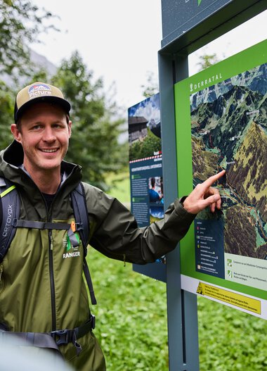 Ein Mann erklärt einer Gruppe von Kindern eine Karte im Kleinwalsertal, um Wissensvermittlung im Naturschutzgebiet | © Kleinwalsertal Tourismus eGen • Fotograf: Oliver Farys