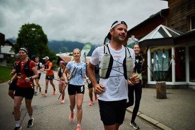 Menschen beim Community Run Adidas Terrex im Kleinwalsertal, die mit Lauf- und Wanderschuhen unterwegs sind, bei bedecktem Himmel. | © Kleinwalsertal Tourismus eGen • Fotograf: Oliver Farys