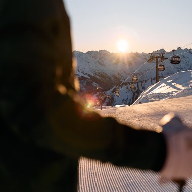 Ski-Alpin-Fahrer in der Abendsonne in Ifen, mit Skiberg und Sessellift im Hintergrund, bei Sonnenuntergang. | © Kleinwalsertal Tourismus eGen • Fotograf: Oliver Farys