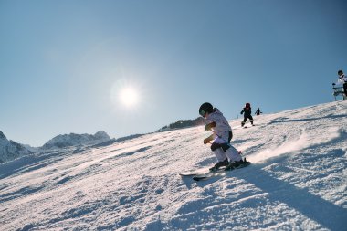 Kleines Kind beim Skifahren auf einer schneebedeckten Piste, sonniger Tag, andere Kinder im Hintergrund, Berg im Hintergrund. | © Kleinwalsertal Tourismus eGen • Fotograf: Oliver Farys