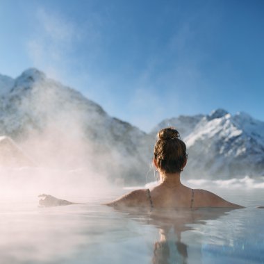 Frau entspannt in einem warmen schönen Spa mit Blick auf verschneite Berge im Kleinwalsertal, umgeben von Nebel und Natur. | © Kleinwalsertal Tourismus eGen • Fotograf: Oliver Farys